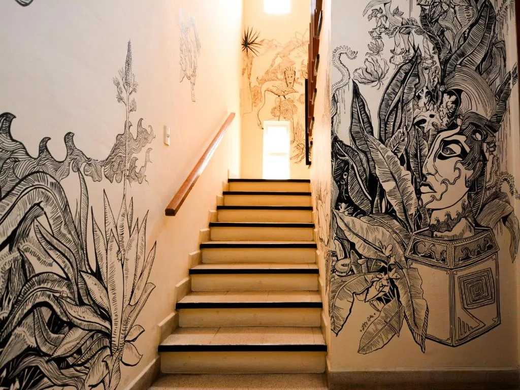 Escalera con murales en tinta de plantas y rostros oaxaqueños